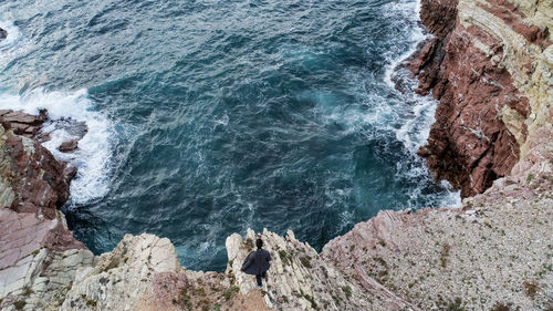 High angle view of man walking on rock against sea