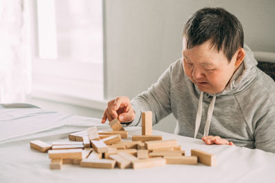 Elderly woman with down syndrome and an asian girl play in tower from wooden blocks