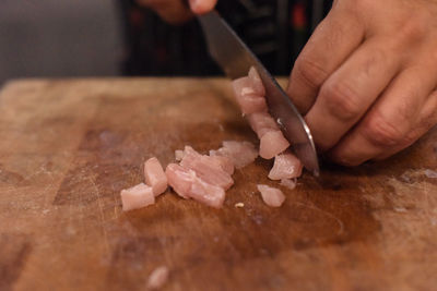 Cropped hands chopping fish on cutting board in kitchen