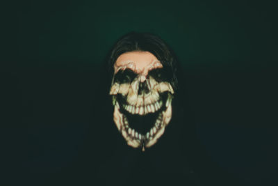 Portrait of person wearing mask against black background