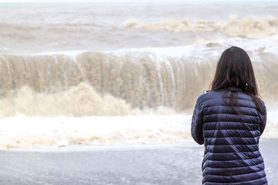 Rear view of woman standing at beach