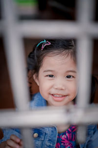 Portrait of cute girl seen through fence