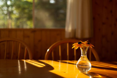 Flower vase on table by window at home