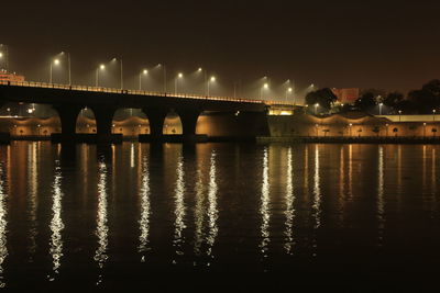 Illuminated bridge over river against sky at night