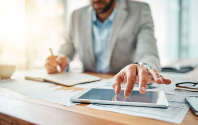 Midsection of businessman working on table