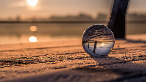 Crystal ball on retaining wall against sky during sunset