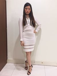 Portrait of young woman standing against wall at home