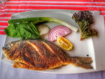 Grilled fish and salad in tray on table