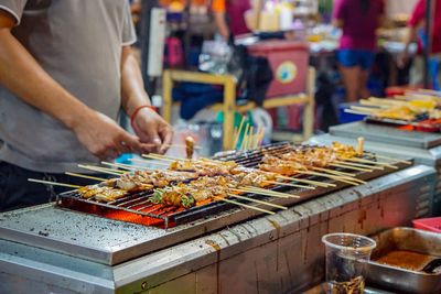 Man preparing food on barbecue grill at market