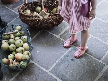 Low section of girl standing by apples in baskets on footpath