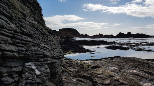 Rock formation on beach against sky