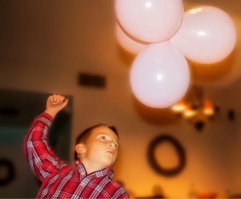 Boy hitting balloons at home