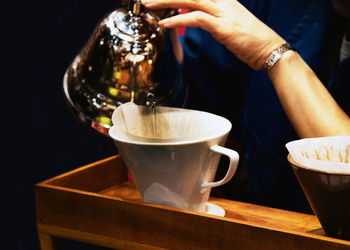 Midsection of woman holding coffee on table