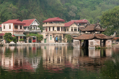 Houses by lake and buildings against sky