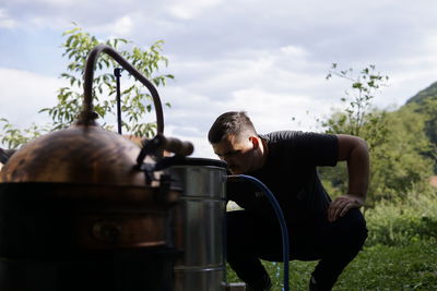 Rear view of a man sitting on plant against sky