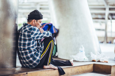 Thoughtful beggar sitting in city