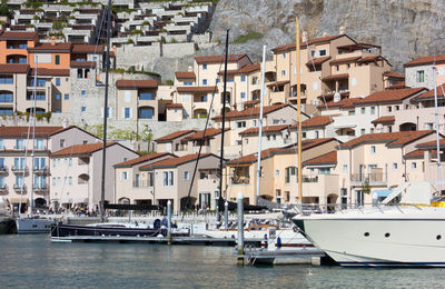 Sailboats moored in town by buildings in city