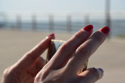 Cropped hands of woman holding mobile phone in sunny day