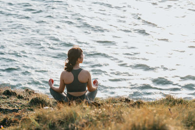 Rear view of woman sitting on beach