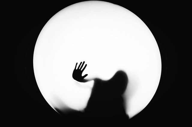 person, indoors, holding, copy space, lifestyles, part of, circle, silhouette, close-up, studio shot, human finger, leisure activity, unrecognizable person, dark, men, cropped, night