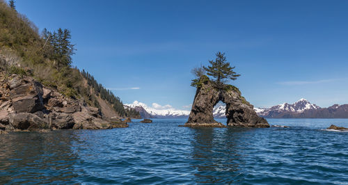 Scenic view of rock formation in sea against blue sky