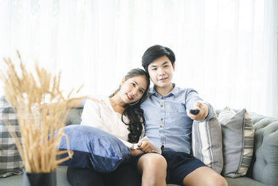 Portrait of a smiling young couple sitting on sofa