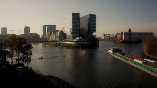 Boats in river by buildings in city against sky