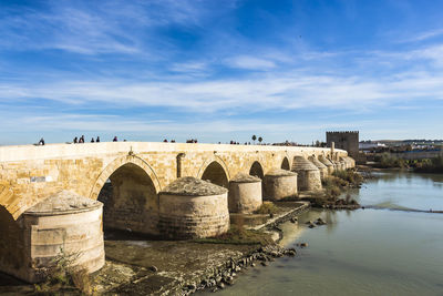 Arch bridge over river against sky