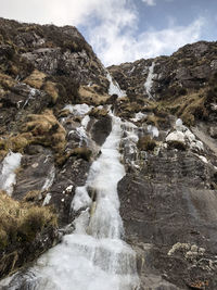 Water flowing through rocks against sky