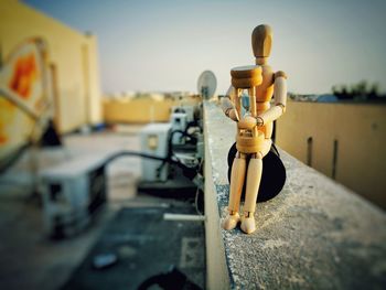 Close-up of figurine on metal against sky during sunset