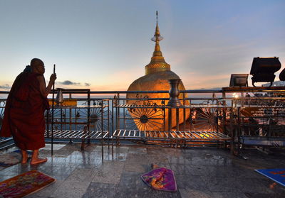 Man standing at temple against sky during sunset