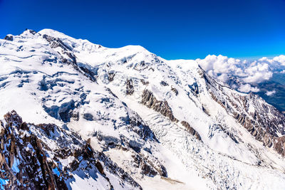 Scenic view of snowcapped mountains against blue sky