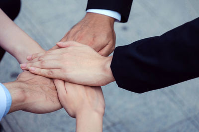 Colleagues stacking hands over footpath