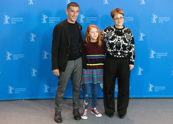 Portrait of friends standing against blue wall