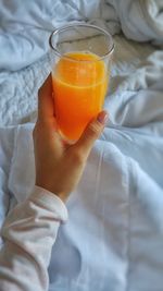 Close-up of hand holding orange juice in glass