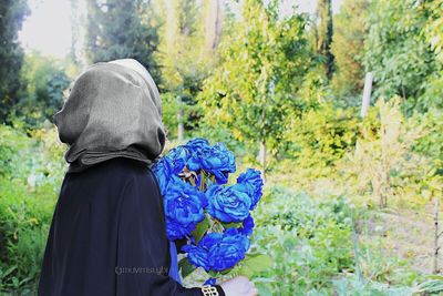 Rear view of woman standing against trees