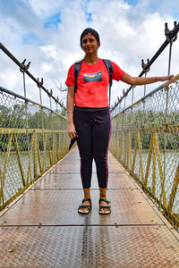 Full length of young woman walking on footbridge