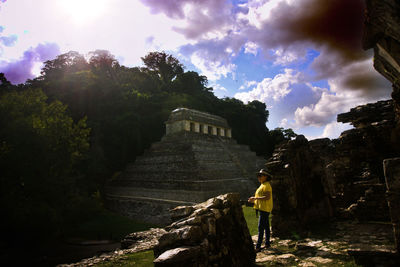 Woman looking at old building against sky