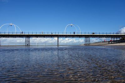 Bridge over water against clear blue sky