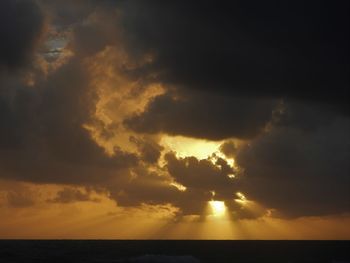 Scenic view of sea against dramatic sky during sunset