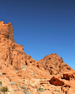 Low angle view of rocky mountain against blue sky