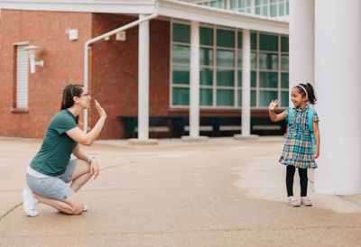 Young millennial mother sending daughter off back to school