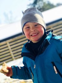 Portrait of smiling boy holding food during snowy weather