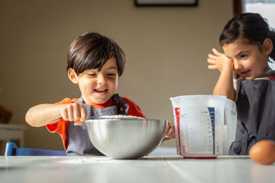 Two children wearing grey aprons baking cookies
