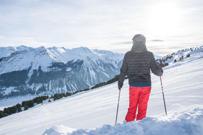 Rear view of person skiing on snowcapped mountain against sky