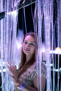 Portrait of young woman in illuminated room