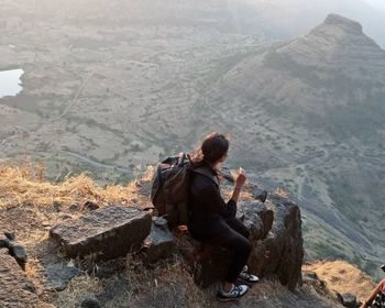 Man sitting on rock looking at mountains