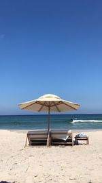 Deck chairs on beach against clear blue sky