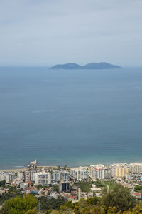 High angle view of city by sea against sky