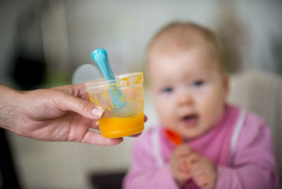 Cropped hand holding food against baby girl